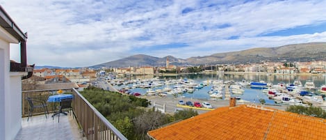 A balcony with a view of a marina, boats, and a mountainous landscape.