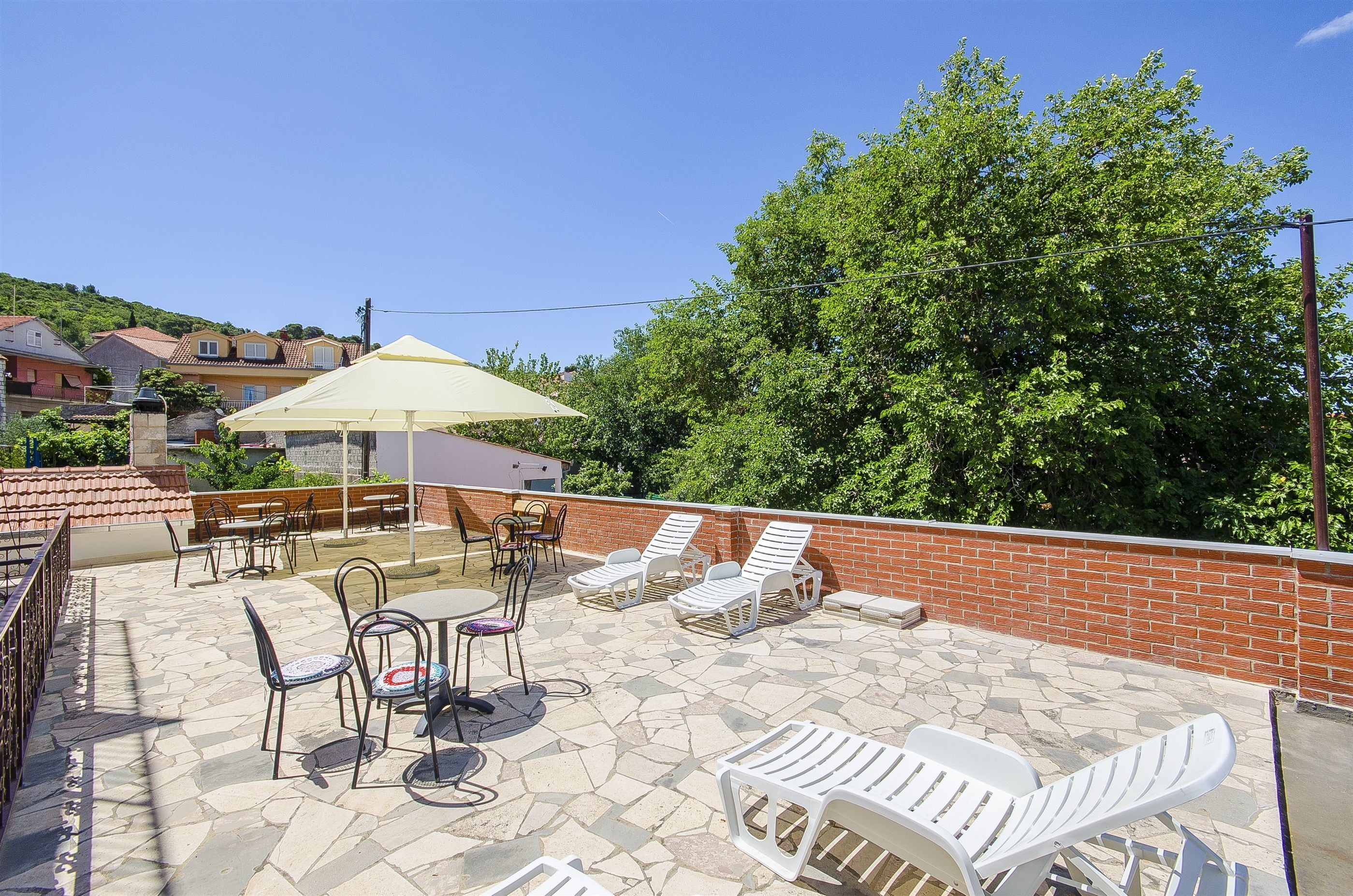 A rooftop terrace with outdoor seating, a table, and a sun umbrella.