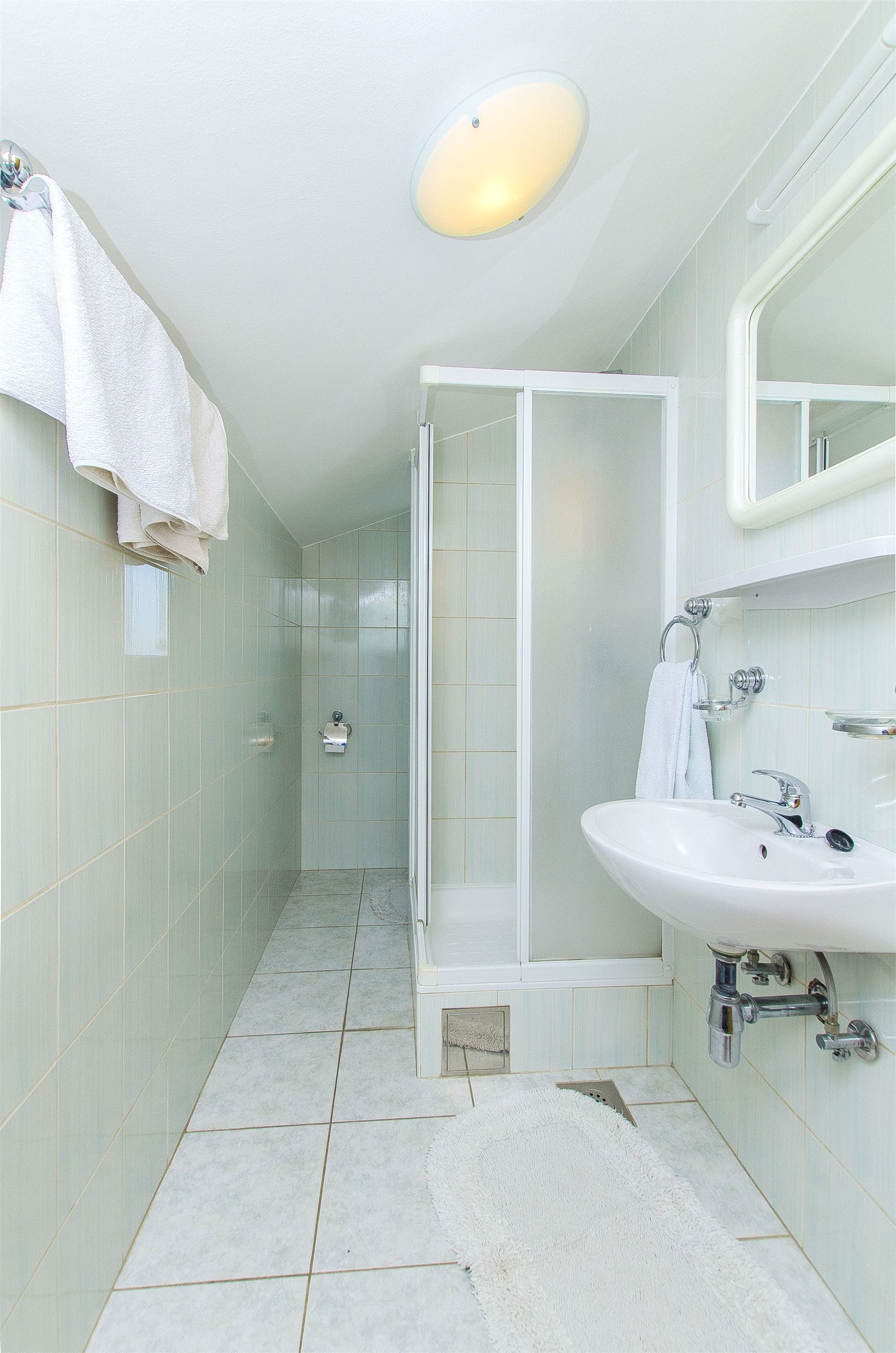 A bathroom with a shower, sink, and mirror.
