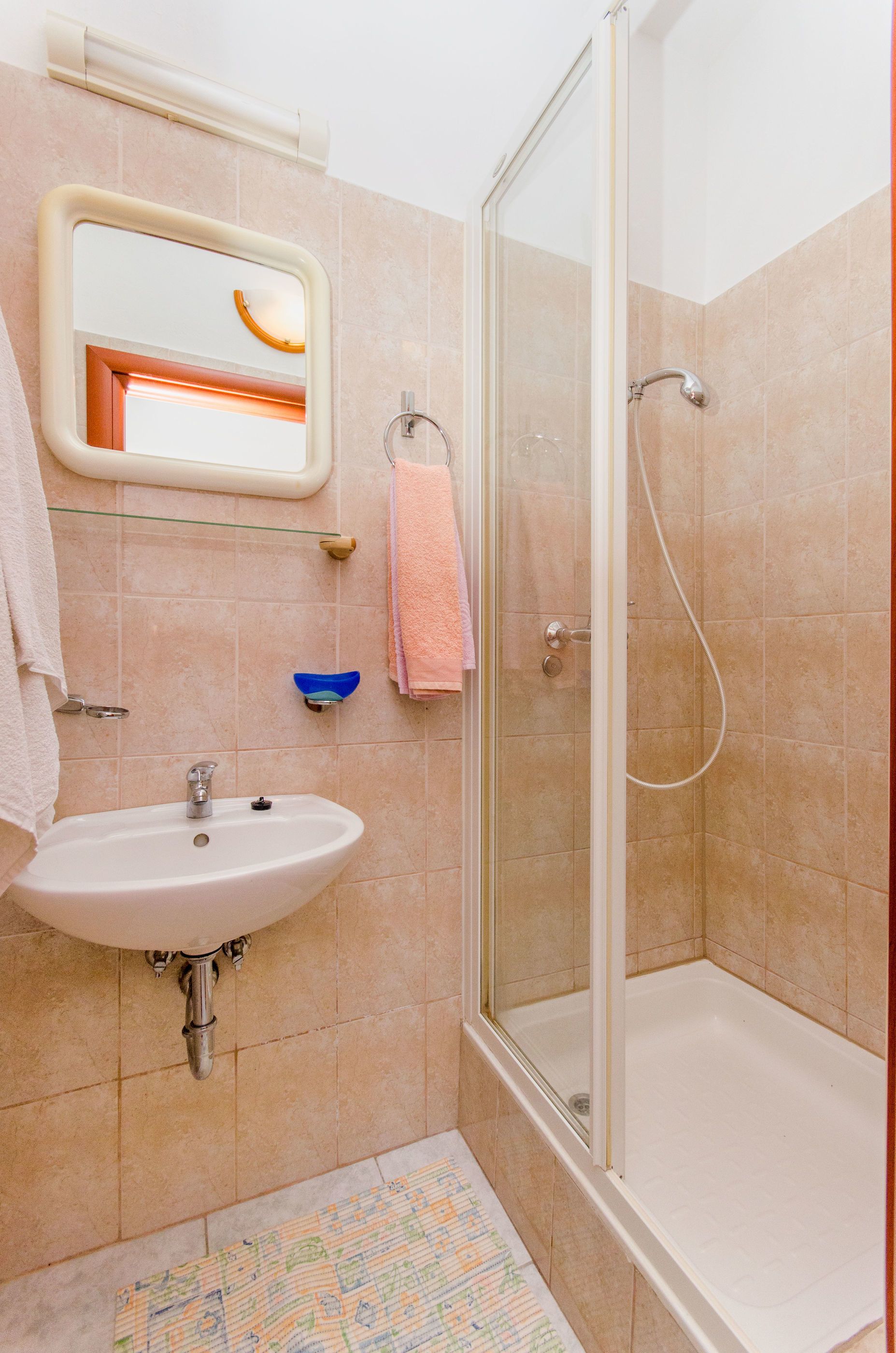 A bathroom with a sink, mirror, and shower.