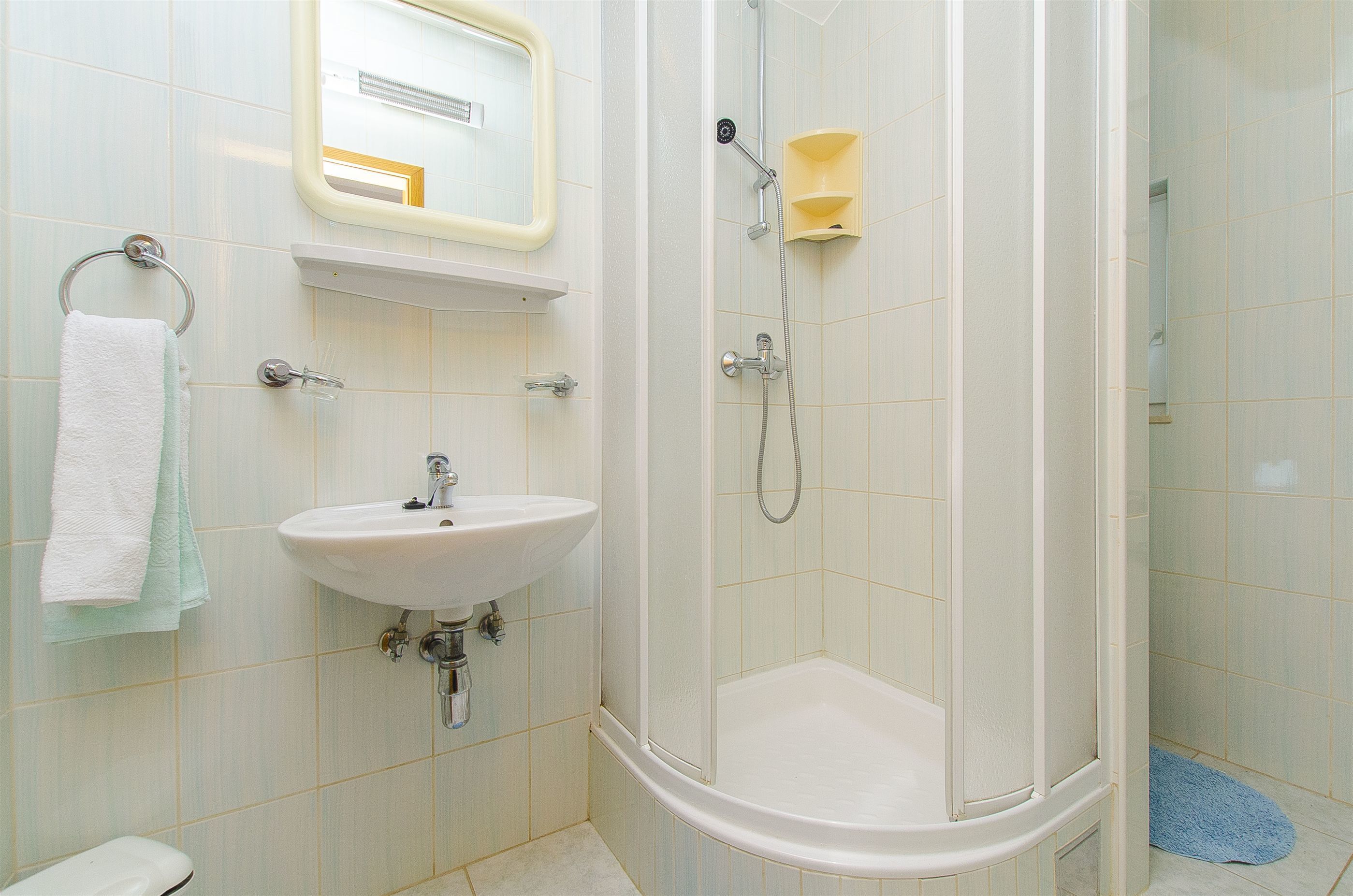 A bathroom with a sink, mirror, and shower.