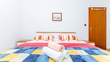 Un letto rifatto con cura, una coperta a quadri, due cuscini e due asciugamani arrotolati.