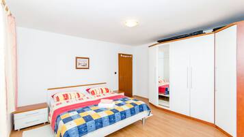 A bedroom with a bed, a wardrobe, a bedside table, and a door.