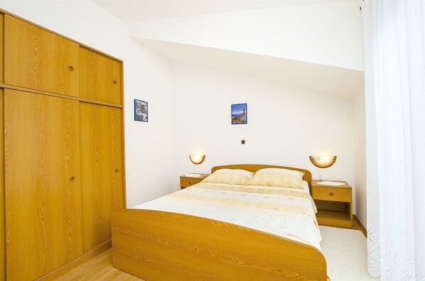 A bedroom with a wooden bed, nightstands, and a wardrobe. - Apartments and Rooms Iva (Trogir)
