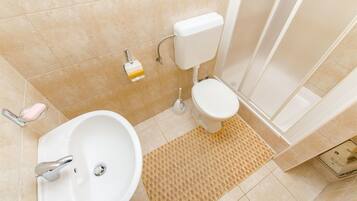 A bathroom with a white sink, toilet, and shower area.