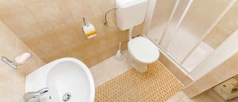Une salle de bain avec un lavabo blanc, des toilettes et un espace douche.