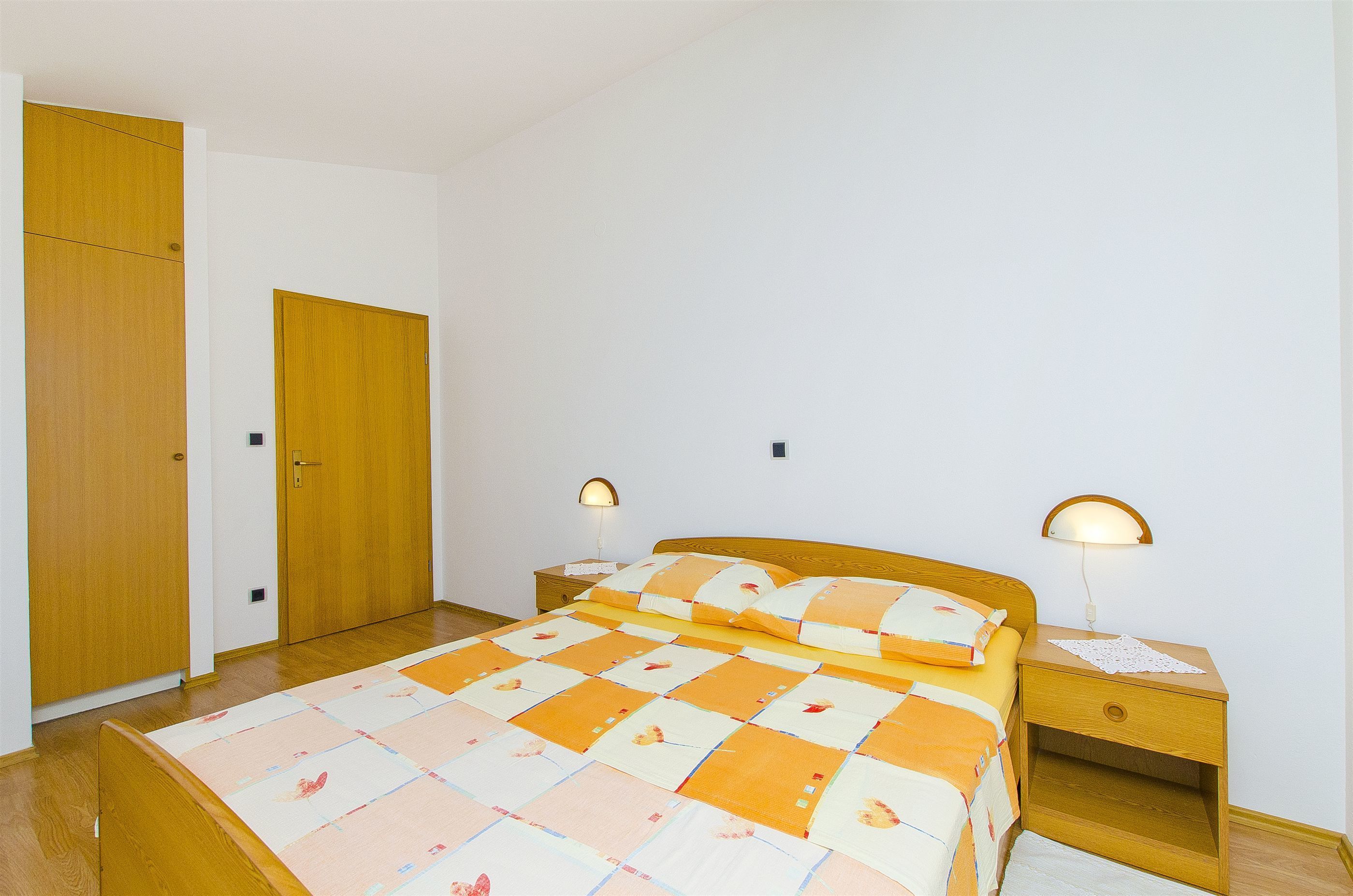 Una camera da letto con un letto, un armadio in legno e due lampade ai comodini.
