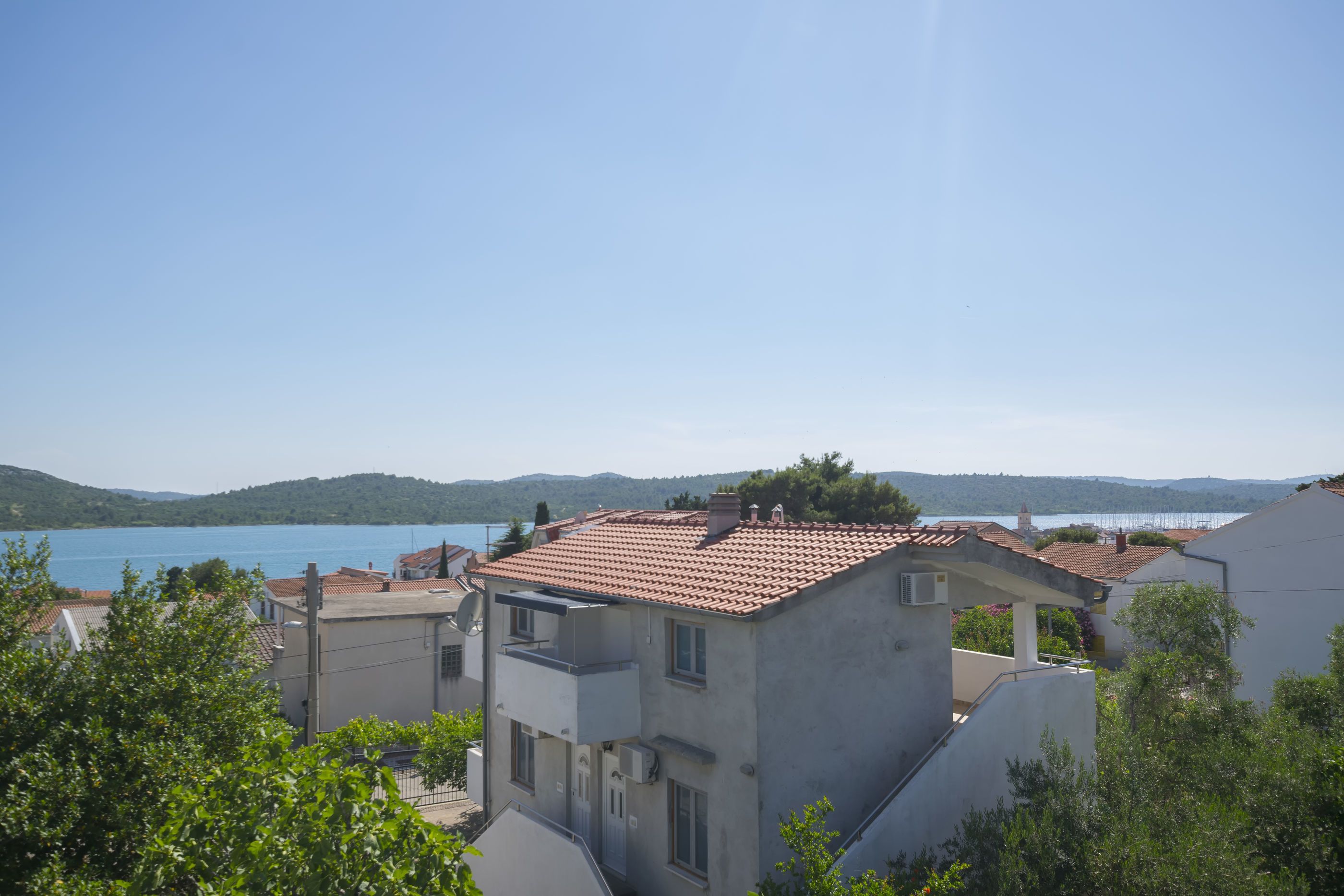 Zona residencial con casas, cielo azul despejado y un lago al fondo.