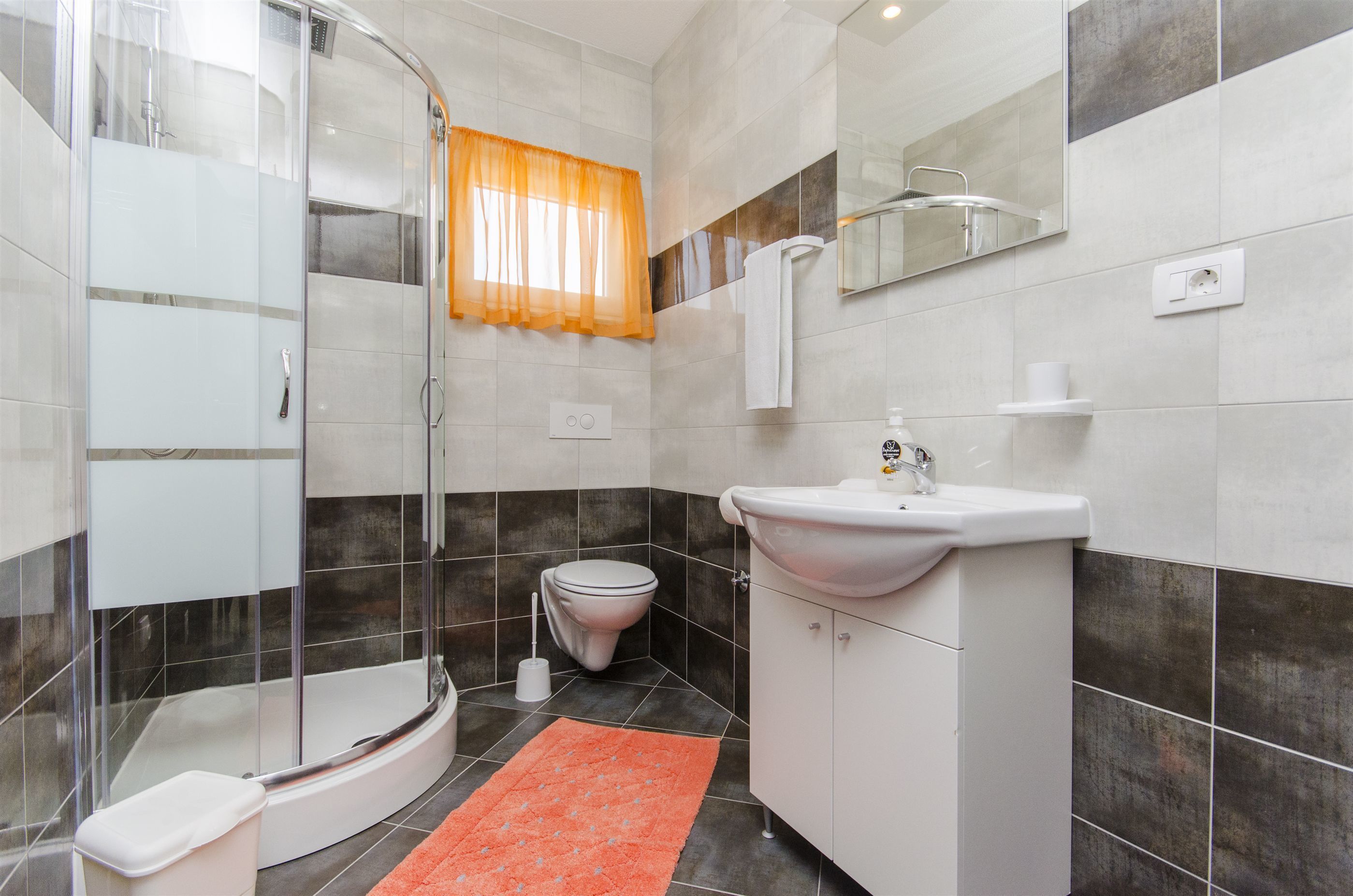 Un baño moderno con ducha acristalada, lavabo blanco y inodoro.