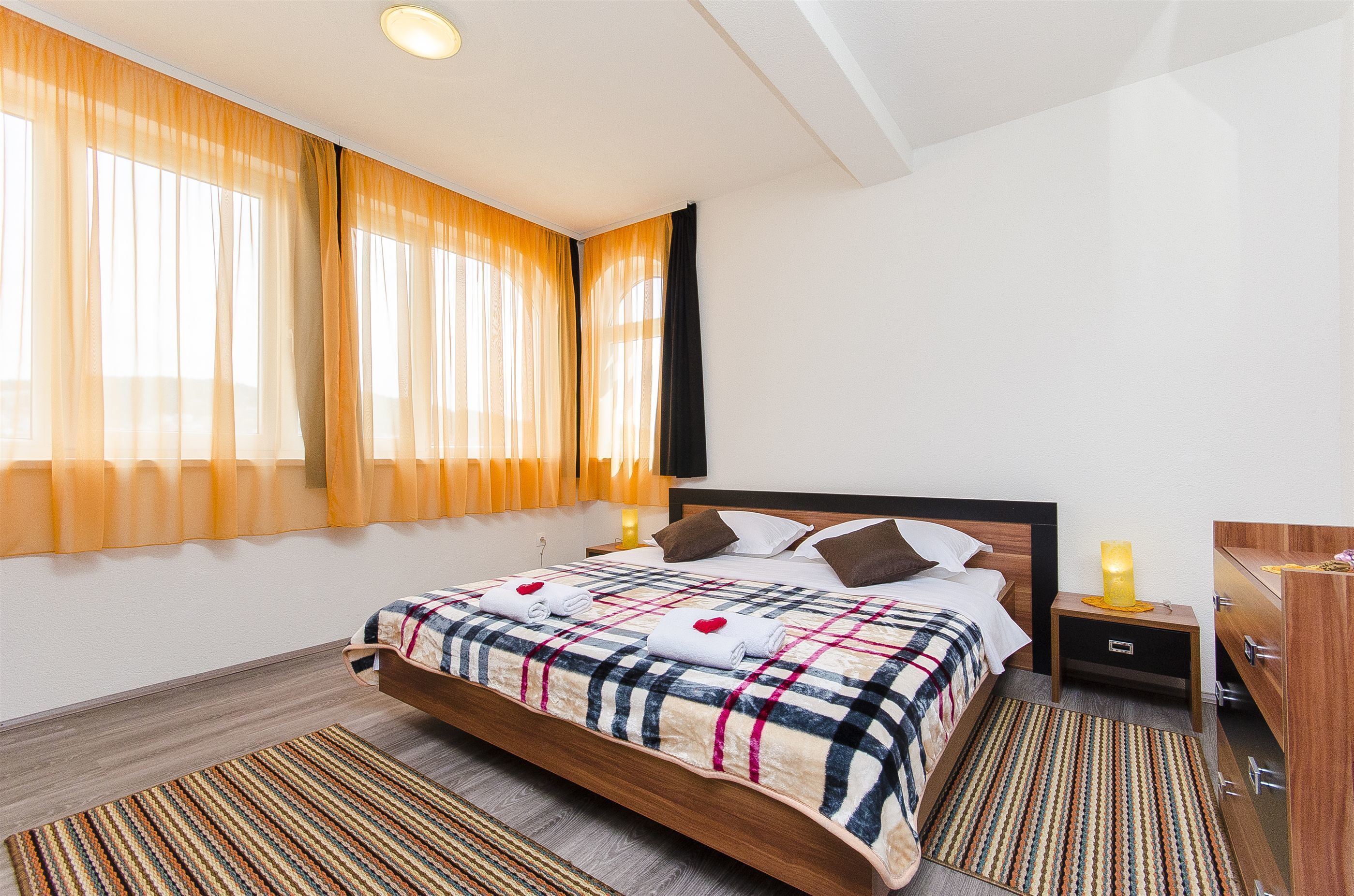 Une chambre d’hôtel avec un lit, des tables de chevet, une commode, un meuble à tiroirs et une fenêtre avec des rideaux.
