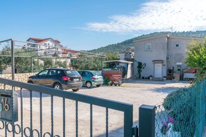 A building with a red roof, a gravel driveway, and parked cars.