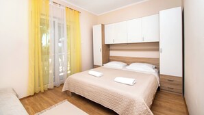 A bedroom with a bed, a wardrobe, and a window with yellow curtains. - Apartment Ivan Vrsi (Vrsi)