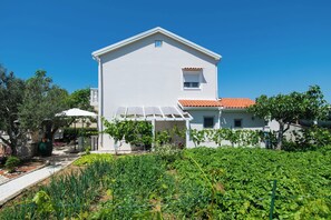 Ein weißes Gebäude mit rotem Ziegeldach, einem kleinen Fenster und einer überdachten Terrasse.