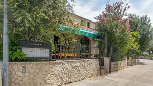 A stone wall, a signboard, and a building with a green awning. - Apartments and Room Central Position (Novalja)