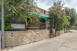 A stone wall, a signboard, and a building with a green awning.