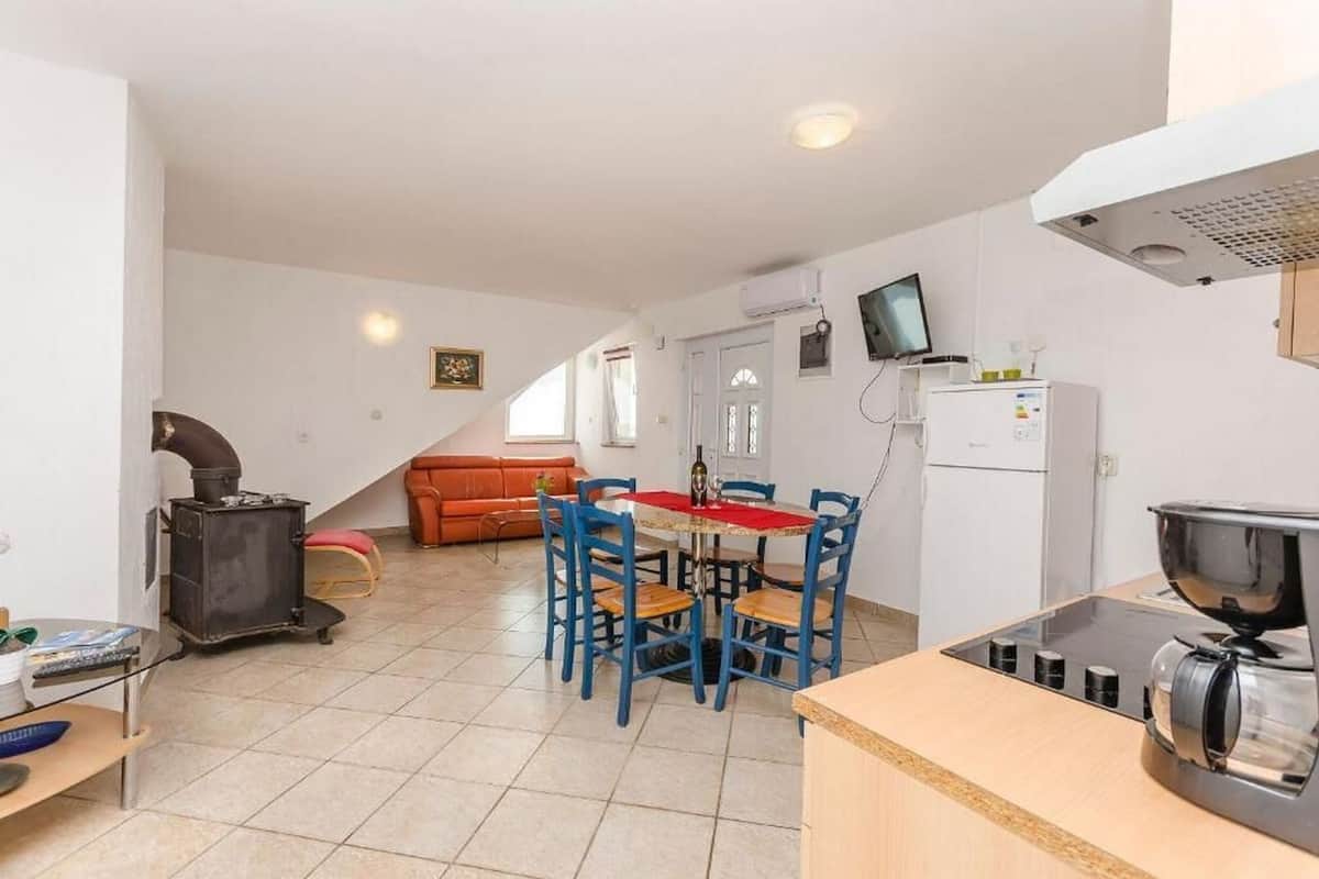 Una cocina compacta con comedor, sofá y televisor.