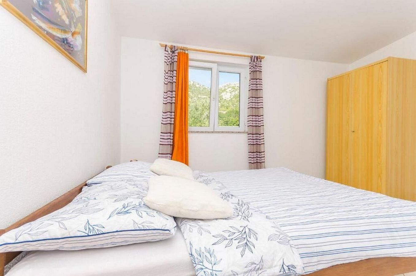 A bedroom with a bed, a window with curtains, and a wardrobe.