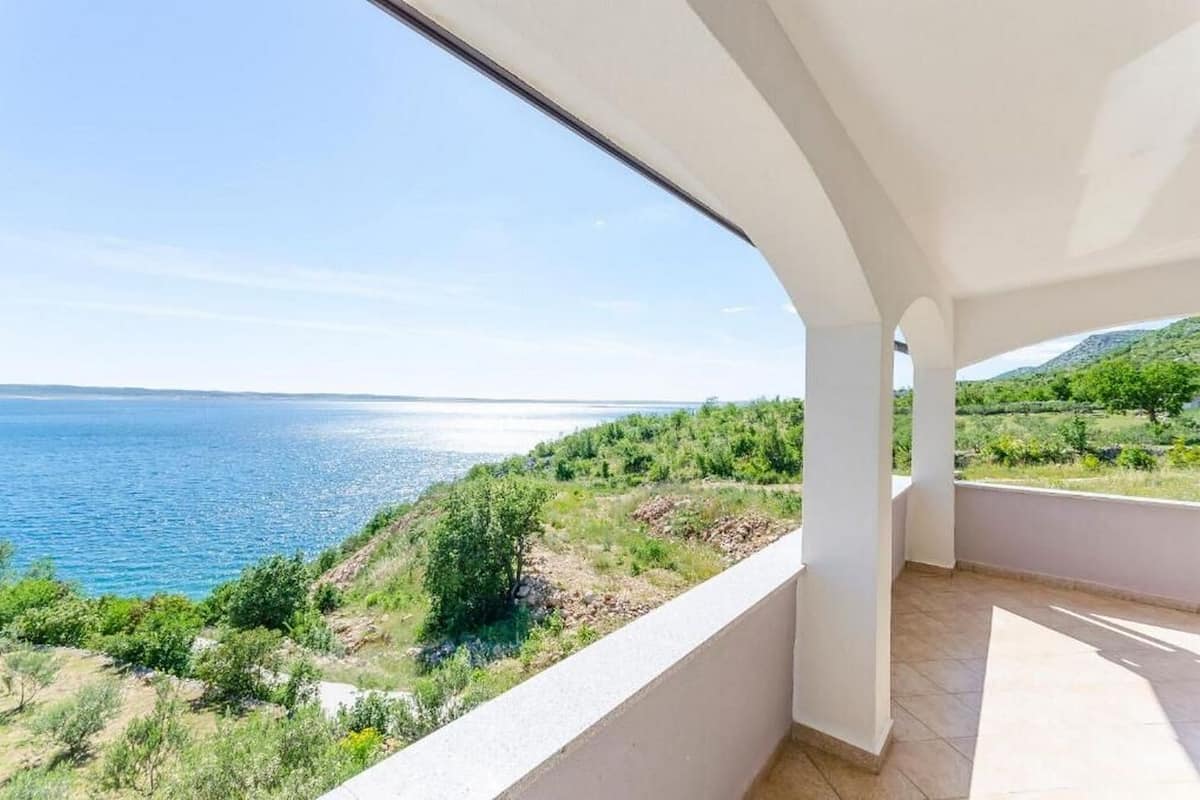 Un balcón con vistas al mar y vegetación.