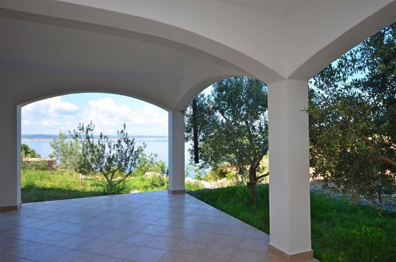 An open terrace with a view of the sea and greenery.