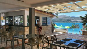 A terrace with outdoor seating, a bar area, and a view of the sea. - Apartments Villa Niko (Arbanija)