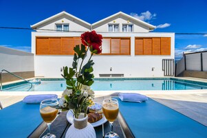 Una piscina al aire libre, sombrillas, sillones reclinables de piscina