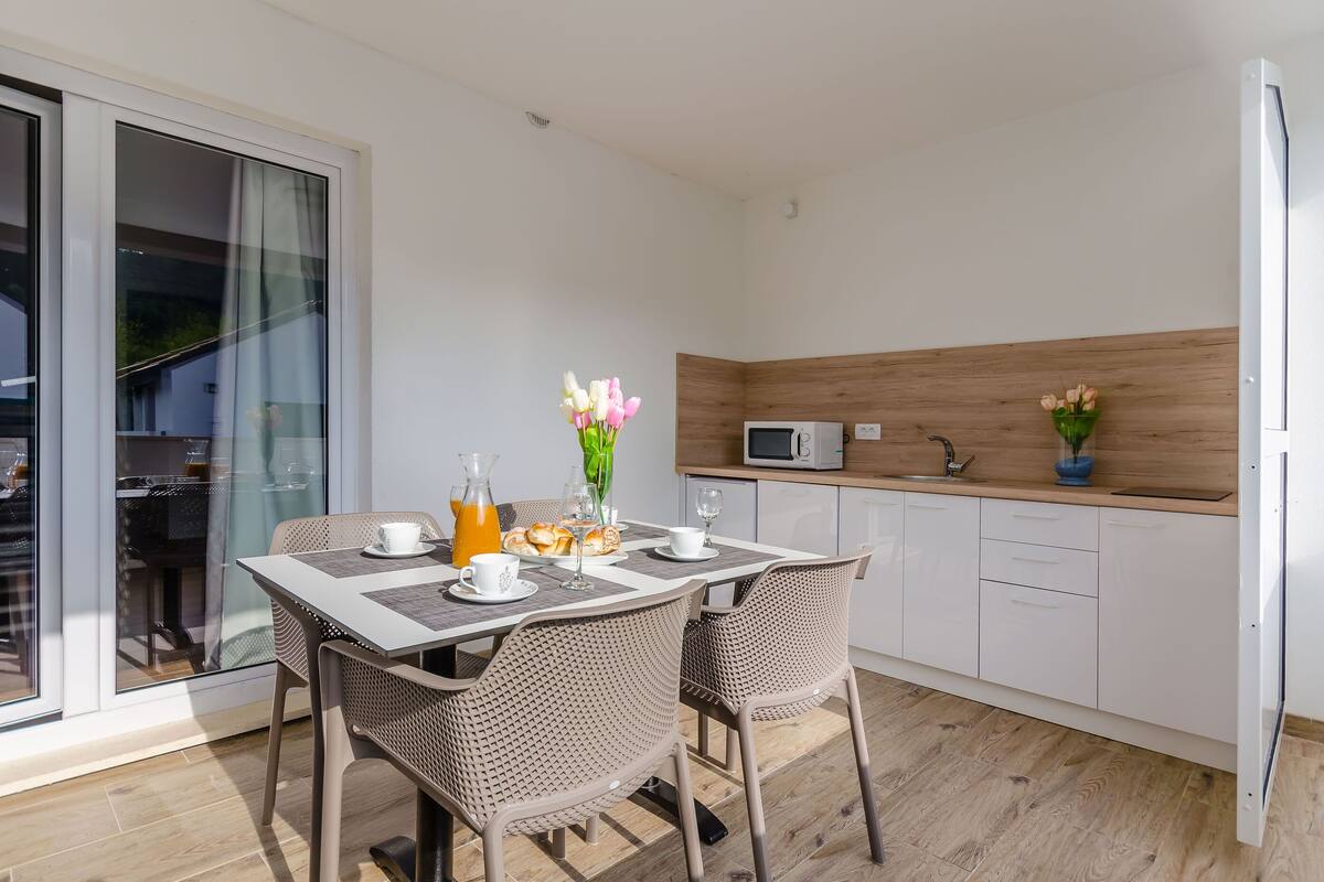Een moderne keuken met witte kastjes, een magnetron en een houten aanrecht.