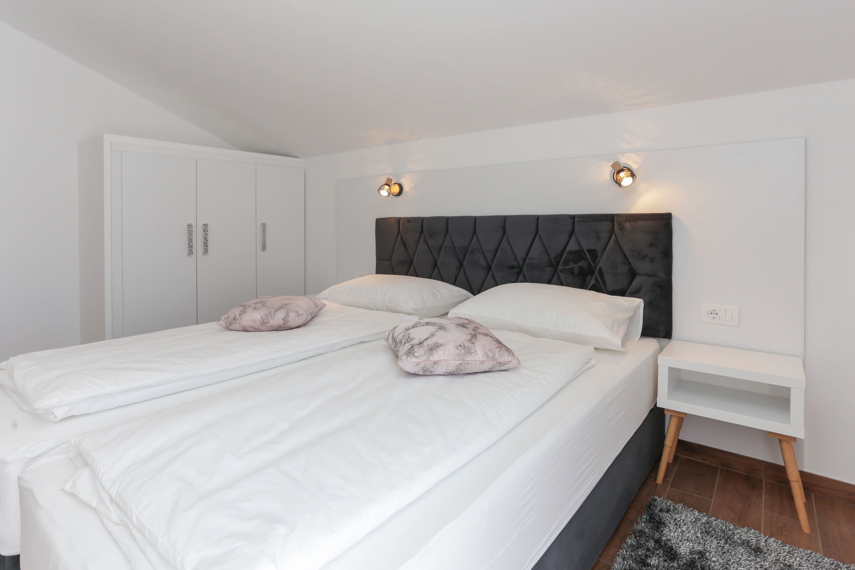 Une chambre à coucher bien rangée, avec un grand lit, deux tables de chevet et une armoire.