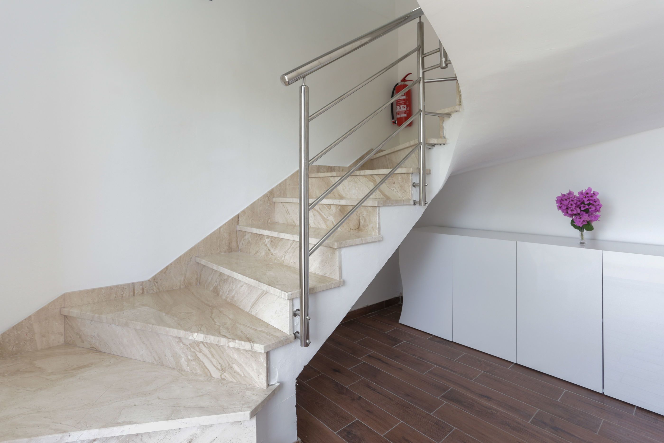 Eine Treppe mit Metallhandlauf und einem an der Wand befestigten Feuerlöscher.