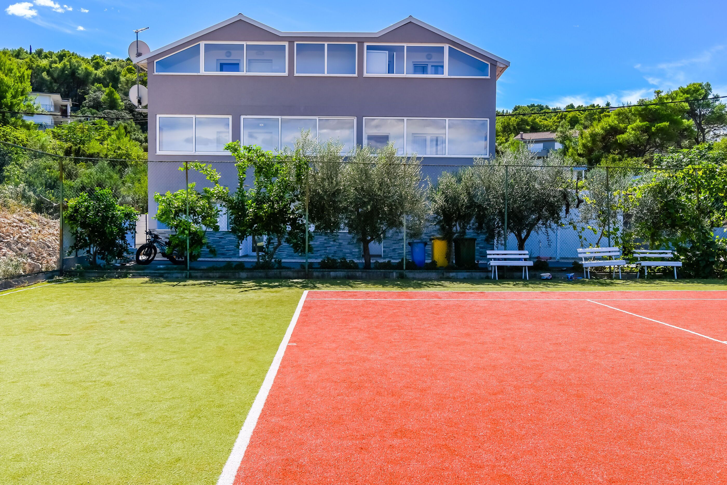 Een tennisbaan met een gebouw op de achtergrond.