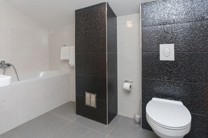 Un baño moderno con bañera, inodoro y zona de ducha.