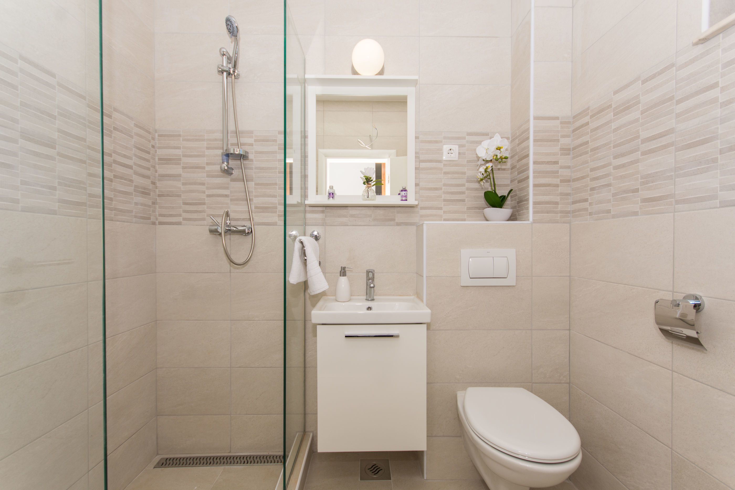 A modern bathroom with a glass-enclosed shower, a white sink, and a toilet.