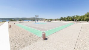 Un terrain de basket-ball en plein air, doté d’une surface de jeu verte et d’un panier de basket.