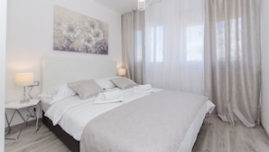 Un dormitorio moderno con una cama grande, una mesita de noche, una lámpara y un cuadro en la pared.