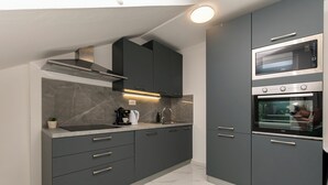 Een moderne keuken met grijze kastjes, een ingebouwde oven en een roestvrijstalen afzuigkap.
