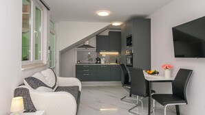 Een moderne keuken met donkere kastjes, een inbouwoven en een eethoek met een tafel en stoelen.