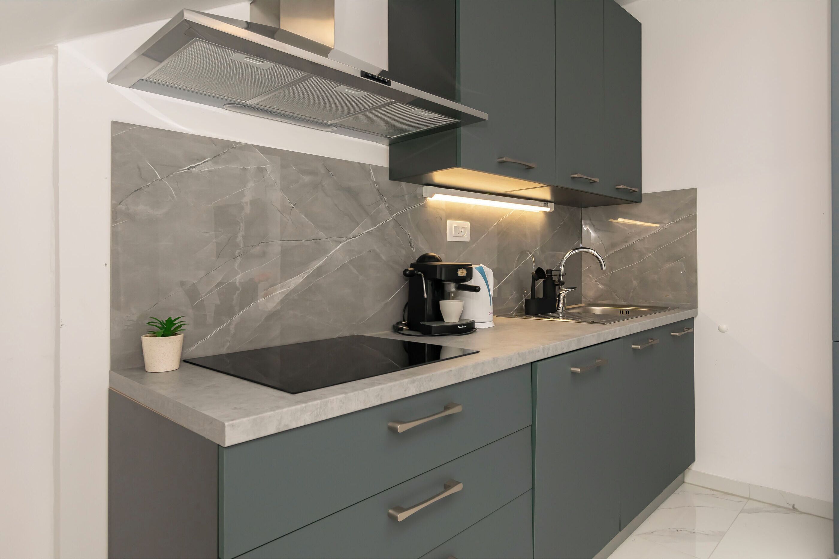 A modern kitchen with a built-in stove, a coffee maker, and a sink.
