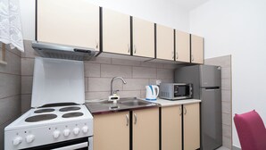 Una cocina compacta con estufa, microondas y refrigerador.