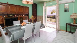 Un comedor con una mesa dispuesta para cuatro, chimenea de ladrillo y vistas al exterior.