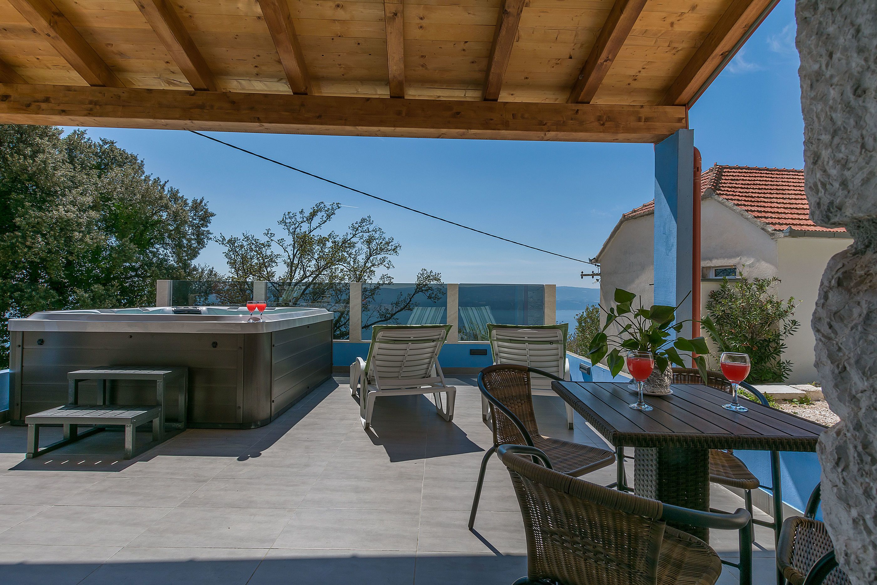 Un espace extérieur abrité comprenant un jacuzzi, des chaises longues et une table avec des boissons.