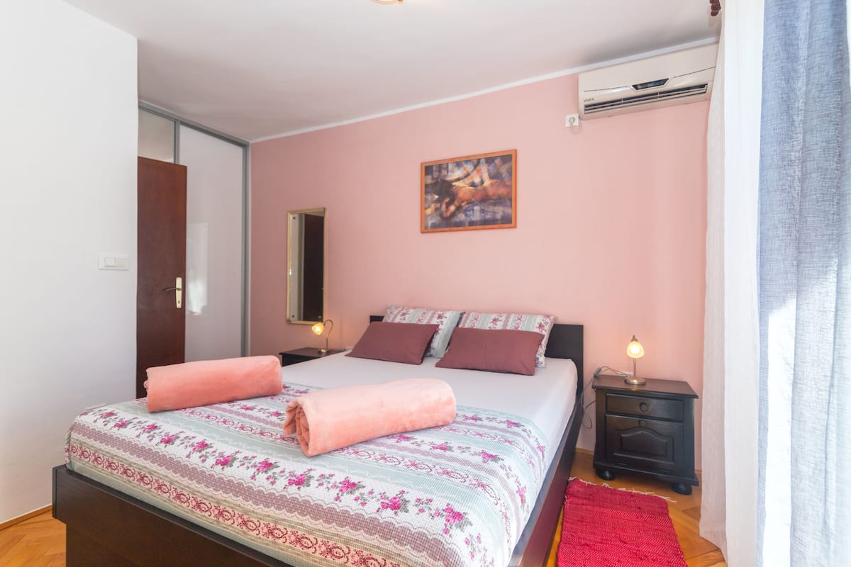 Una camera da letto con un letto, comodini, un quadro e un condizionatore.