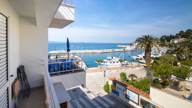 A balcony with a view of a marina, boats, and a clear sky. - Apartments Matko (Podgora)