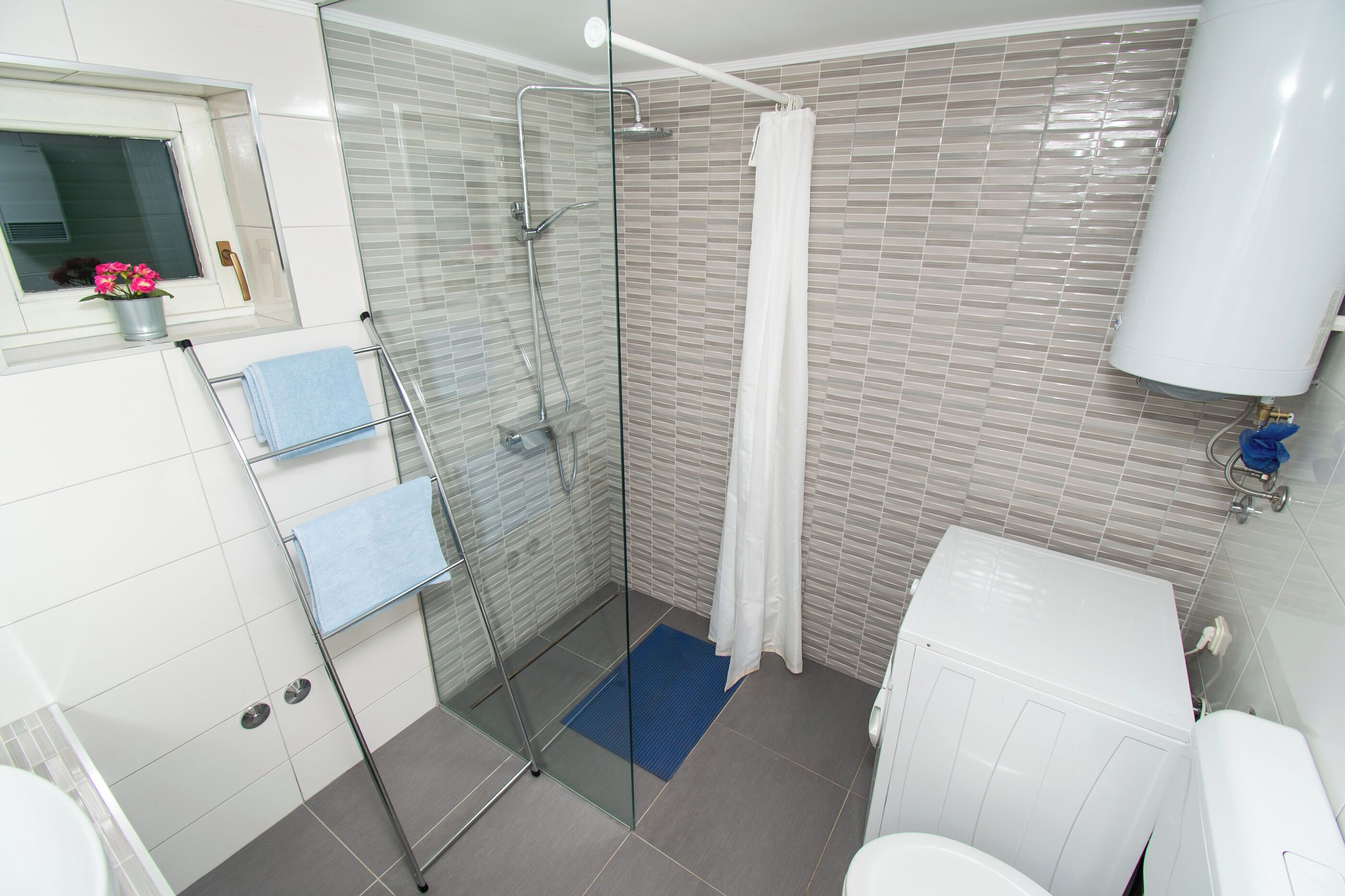 Een moderne badkamer met een douchecabine van glas, een toilet en een wastafel.