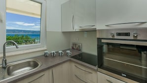 A kitchen with a view of the sea, a sink, and an oven. - Apartments Villa Aquamarine (Duce)