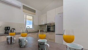 A kitchen with four coffee mugs on the counter, a refrigerator, and an oven. - Apartments Villa Aquamarine (Duce)