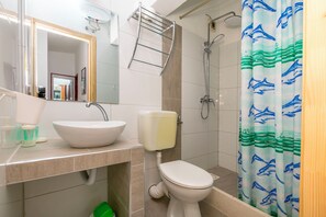 A bathroom with a white sink, toilet, and shower. - Apartment Garden by the sea (Rogoznica)