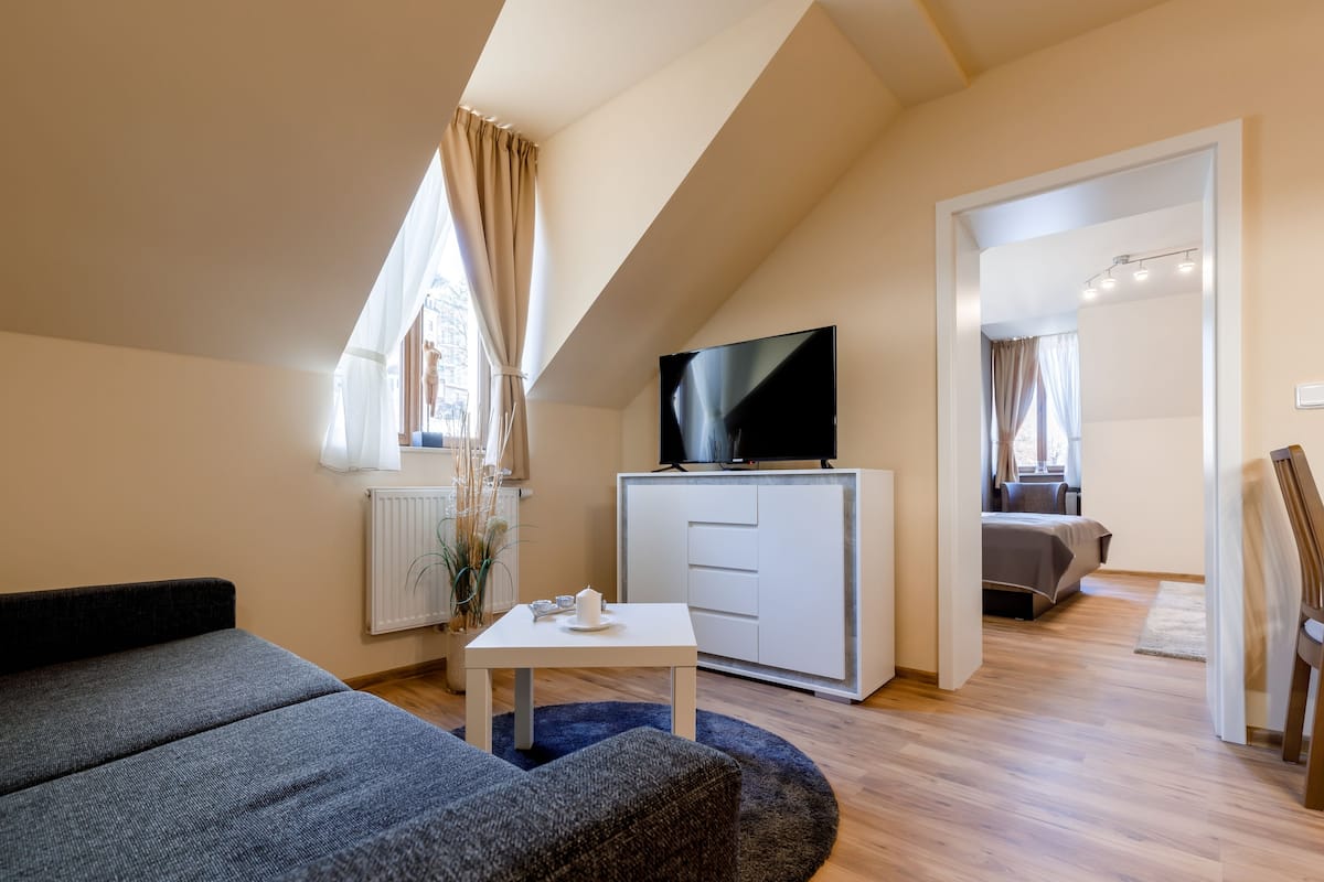 A modern living room with a sofa, a coffee table, a flat-screen TV, and a white cabinet.