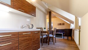 A modern kitchen with wooden cabinetry and a dining area with a table and chairs. - Apartments Menuet (Karlovy Vary)