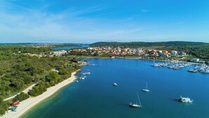 Vista aérea de un pueblo costero con un puerto deportivo, barcos y una playa.