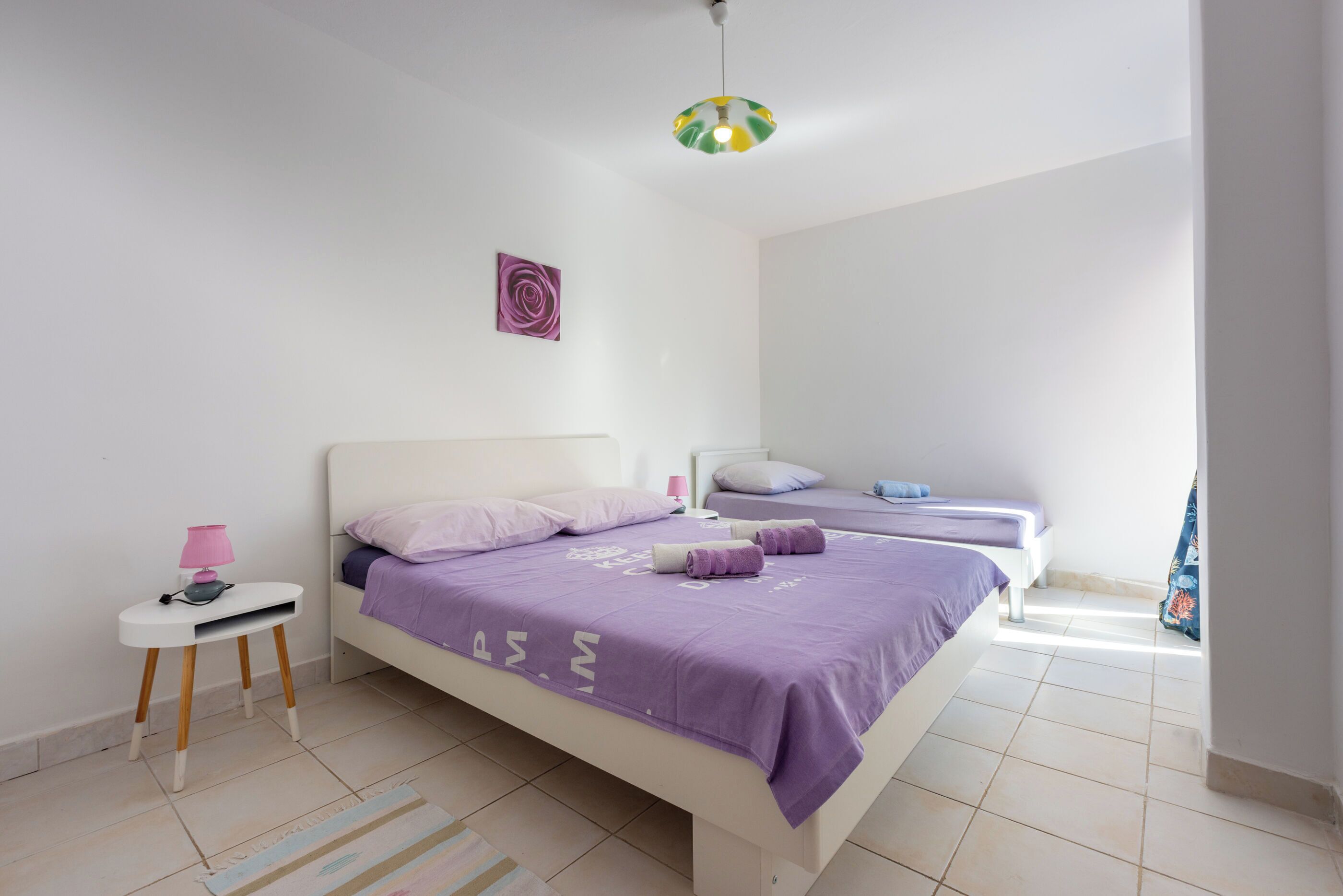 A bedroom with a bed, a bedside table, a lamp, and a ceiling light.