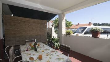 An outdoor patio with a table set for breakfast, including croissants, fruit, and beverages.